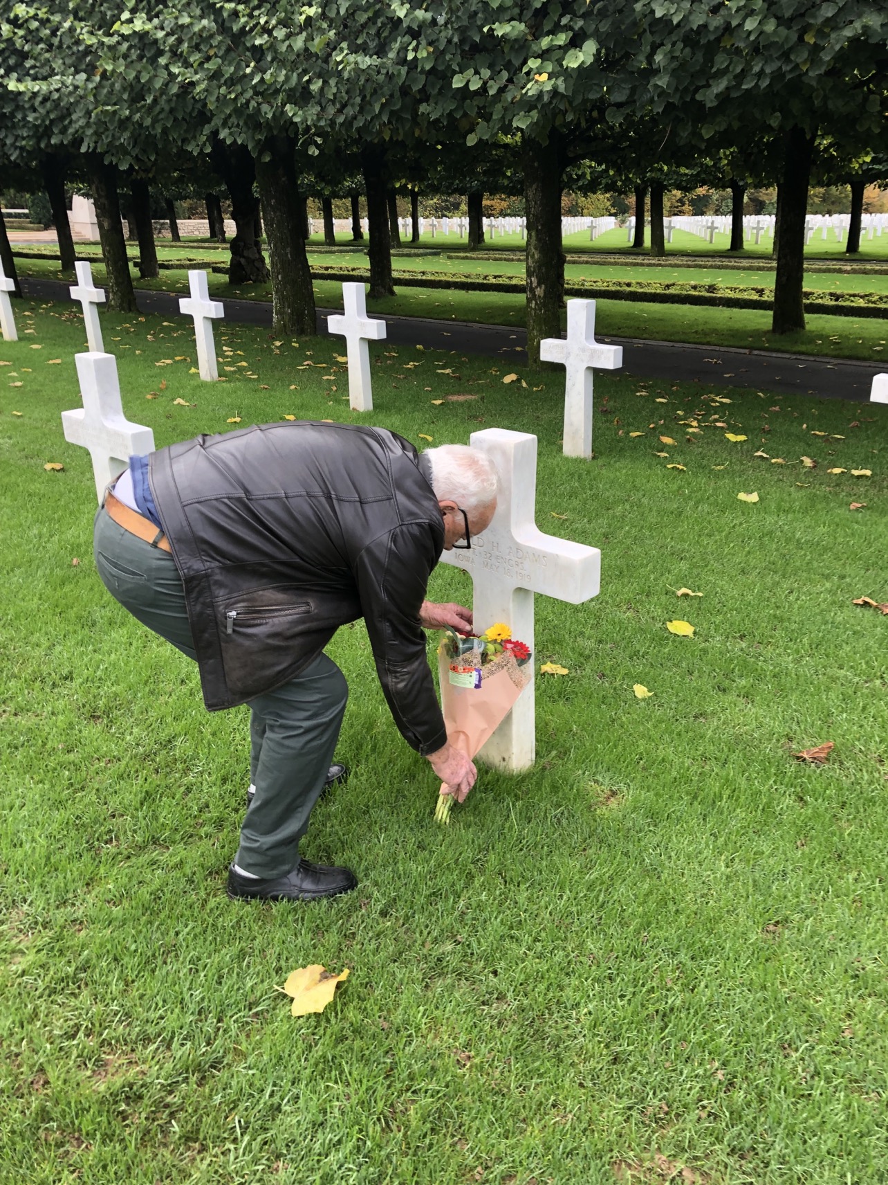A French visitor flowering a headstone during All-Saints Day at St. Mihiel American Cemetery Credits: American Battle Monuments Commission.