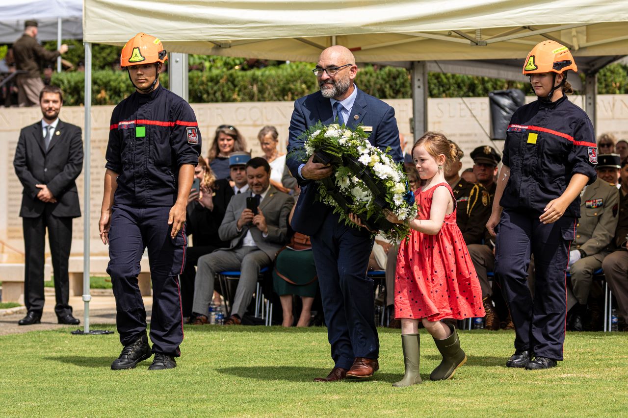 The cemetery superintendent and his daughter carry a wreath to place during the ceremony