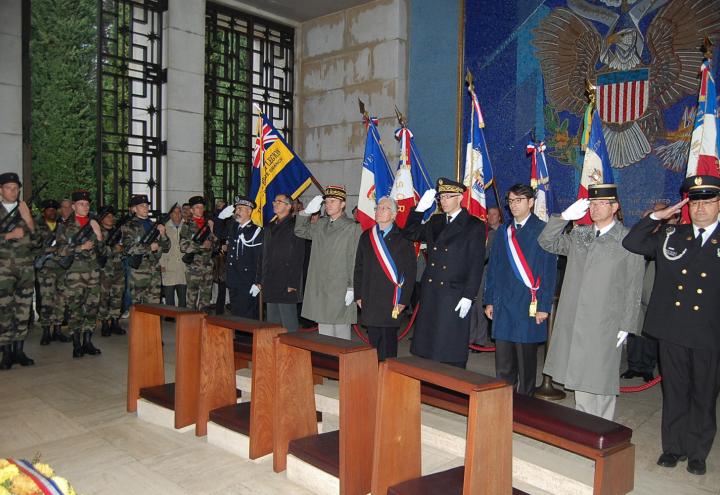 Participants salute in the chapel in front of a mosaic wall during the 2012 Veterans Day ceremony at Rhone American Cemetery. 