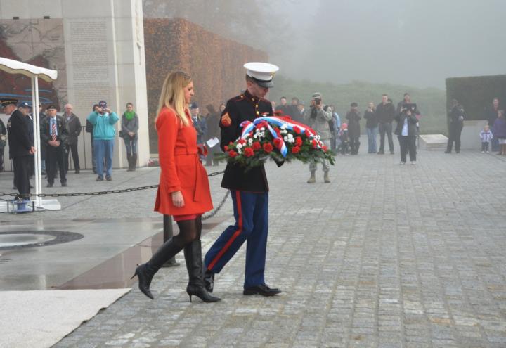 ABMC Commissioner Maura Sullivan walks with a marine holding a floral wreath.