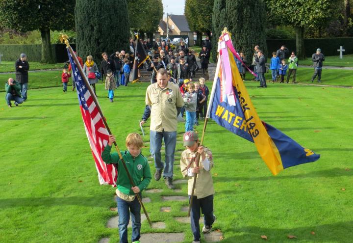 Boy scouts process with flags into the cemetery. 