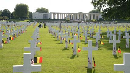 Rows upon rows of headstones have the American and Belgian flags. 