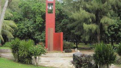 Amidst greenery, a memorial area includes a granite column. 
