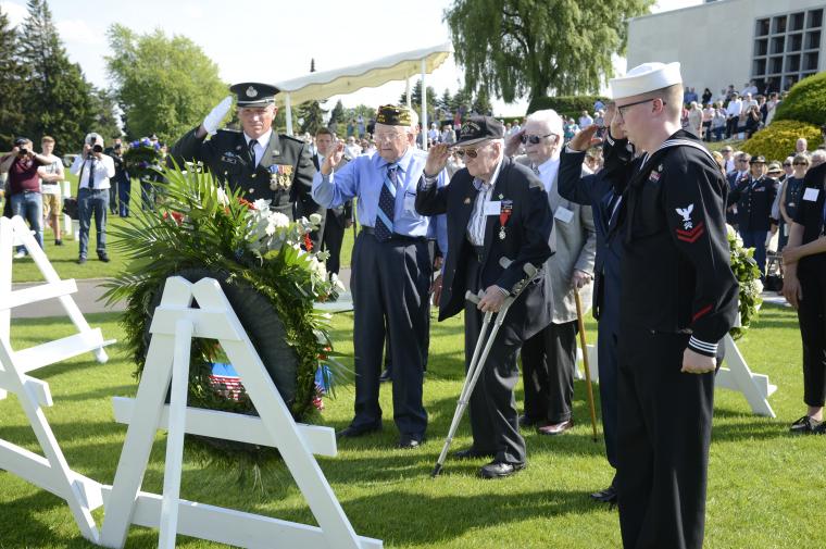Men salute after laying a wreath.