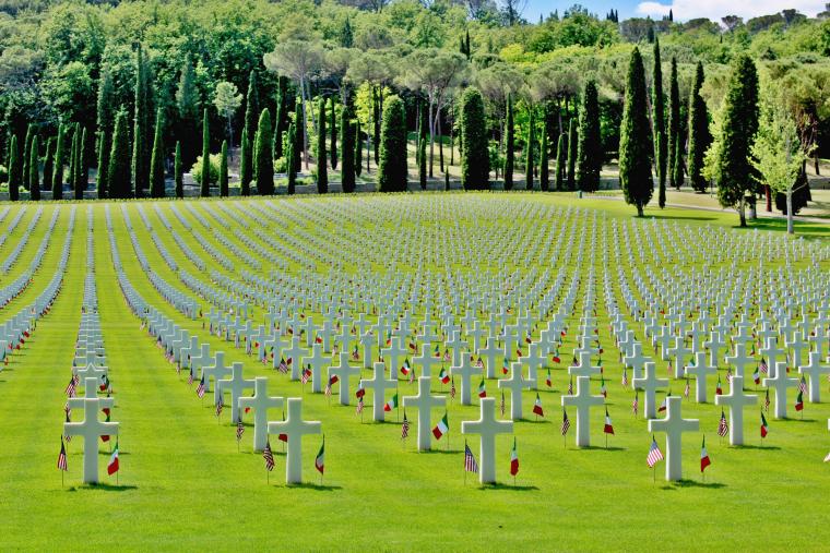 Rows and rows of headstones with flags cover the ground. 