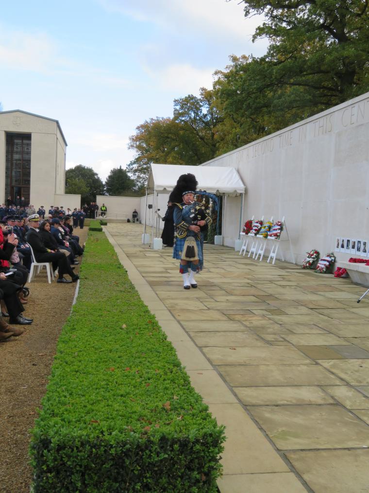 A bag piper walks in front of the Tablets of the Missing while he plays.