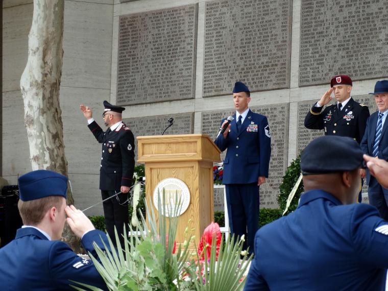 An airman sings the national anthem from the podium area.